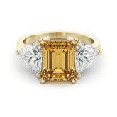 A gold ring with a large yellow gemstone in the center, flanked by two smaller diamonds on either side.