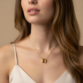 A close-up of a woman's neck and chest area, featuring a gold necklace with a large gemstone pendant.