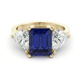 A gold ring with a large blue gemstone in the center, flanked by two smaller diamonds on either side.
