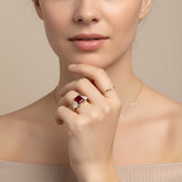 A close-up of a woman's face, with her hand holding a ring on her finger.