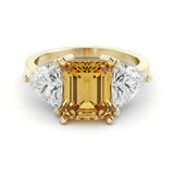 A gold ring with a large yellow gemstone in the center, flanked by two smaller diamonds on either side.