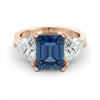 A gold ring with a large blue gemstone in the center, flanked by two smaller diamonds on either side.