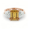 A gold ring with a large yellow gemstone in the center, surrounded by smaller diamonds on either side.