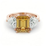 A gold ring with a large yellow gemstone in the center, surrounded by smaller diamonds on either side.