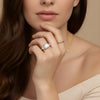 A close-up of a woman's hand wearing a large diamond ring, with her chin resting on her hand.