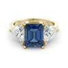 A gold ring with a large blue gemstone in the center, flanked by two smaller diamonds on either side.