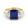 A gold ring with a large blue gemstone in the center, flanked by two smaller diamonds on either side.