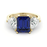 A gold ring with a large blue gemstone in the center, flanked by two smaller diamonds on either side.
