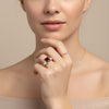 A close-up of a woman's face, with her hand holding a ring on her finger.