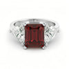 A silver ring with a large, deep red gemstone in the center.