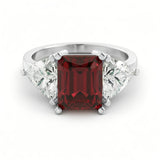 A silver ring with a large, deep red gemstone in the center.