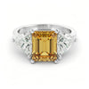 A silver ring with a large yellow gemstone in the center, surrounded by smaller diamonds on either side.