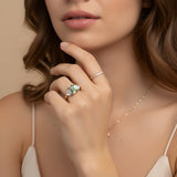 A close-up of a woman's hand wearing a ring and necklace, with her chin resting on her hand.