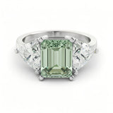 A silver ring with a large, green gemstone in the center, surrounded by smaller diamonds on either side.